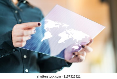 Modern Global And International Business Technology Concept. Businesswoman Using Futuristic Transparent Tablet With World Map On Screen. Export, Foreign Trade And Communication Concept.