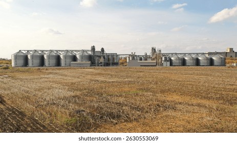 Modern grain elevator complex against a rural backdrop, highlighting agricultural infrastructure and food production processes
