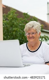 Modern Grandma Talking On The Skype With Family.  Looking At Screen And Smiling