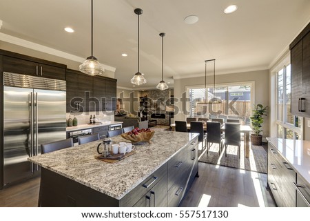 Modern gray kitchen features  dark gray cabinetry paired with white quartz countertops and a glossy gray linear tile backsplash. Bar style kitchen island with granite counter. Northwest, USA
