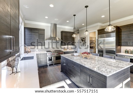 Modern gray kitchen features dark gray flat front cabinets paired with white quartz countertops and a glossy gray linear tile backsplash. Bar style kitchen island with granite counter. Northwest, USA
