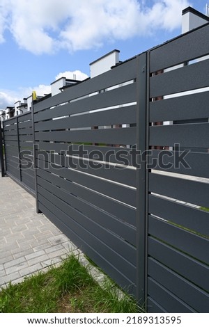 Modern gray metal fence for fencing the yard area. Horizontal metal sections of the fence. Close up.