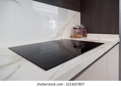 Modern Gray White Lacquer Wood Kitchen Cabinet Equipment And Black Electric Stove On White Granite Countertop In Home