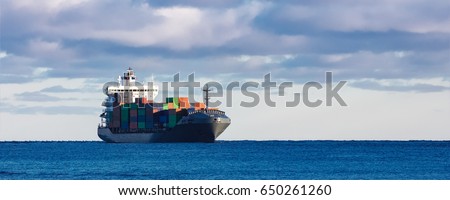 Modern grey container ship moving in still water