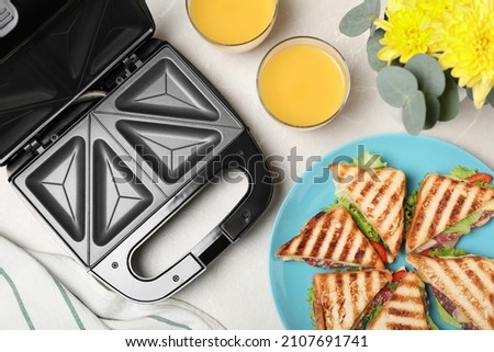 Modern grill maker, juice and sandwiches on white table, flat lay