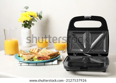 Modern grill maker and sandwiches on white table