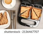 Modern grill maker with tasty sandwiches on light grey table, flat lay