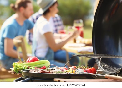 Modern grill with vegetables and blurred people on background - Shutterstock ID 1112523824