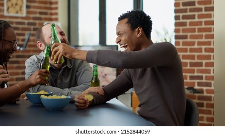 Modern group of friends laughing together at jokes, gathering to have fun with drinks and snacks in living room. Happy men and women smiling and having conversation about board games. - Powered by Shutterstock