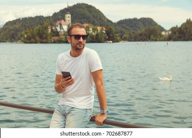 Modern guy using cellphone on the lake.