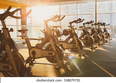 Modern gym interior with equipment. Fitness club with training exercise bikes in evening backlight. - Powered by Shutterstock