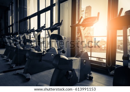 Modern gym interior with equipment. Row of training exercise bikes wheel detail, backlight. Healthy lifestyle concept