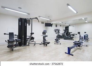 Modern Gym In Leisure Center With Mirror Wall And Fitness Machines