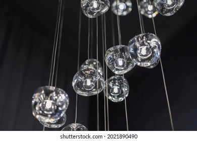 Modern hanging lamp lights with black background. Close-up view of crystal balls of contemporary chandelier