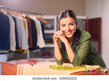 A Modern Happy smiling Young attractive Indian Asian woman or female professional fashion stylist standing in a designer boutique store and looking at the camera. self-employment and startup concept.