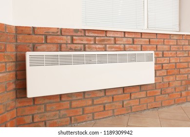 Modern heating convector on brick wall indoors