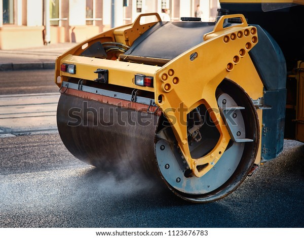 Modern heavy asphalt roller that stack and\
press hot asphalt. Yellow road repair machine. Repairing in modern\
city with vibration roller\
compactor
