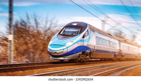 Modern high speed aerodynamic streamlined electric train on rail during sunset passing by with motion blur.

