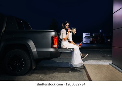 Modern hipster bride and groom is sitting in the car trunk. Wife and husband on the boot of car - Powered by Shutterstock