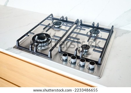 Modern hob gas or gas stove made of stainless steel using natural gas or propane for cooking products on light stoneware countertop in kitchen interior with copyspace.
