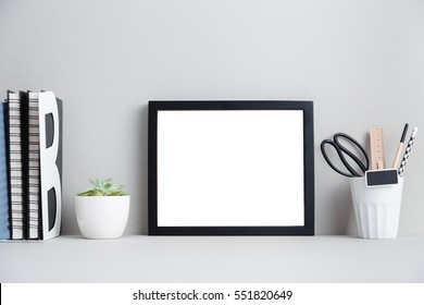 Modern home decor mock up. Creative desk with blank picture frame or poster, desk objects, office supplies, books and plant on a gray background.  - Shutterstock ID 551820649