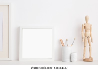 Modern home decor mock up. Creative desk with blank picture frame or poster, wooden mannequin desk objects - Powered by Shutterstock