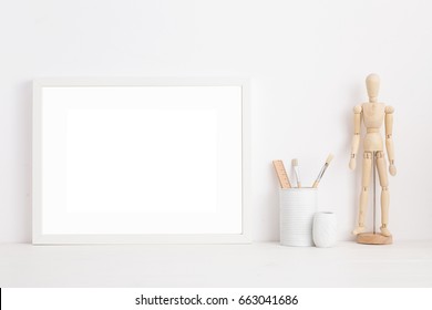 Modern home decor mock up. Creative desk with blank picture frame or poster, wooden mannequin, desk objects. - Powered by Shutterstock