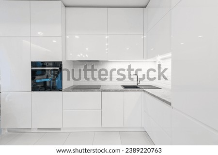 Modern Home Interior. Kitchen with Sink and Black Oven. White Furniture. LED Light. Luxury Home.