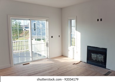 Modern Home Interior With Sliding Glass Doors Leading To A Small Porch And An Unfinished Gas Fireplace Log Insert In The Wall.