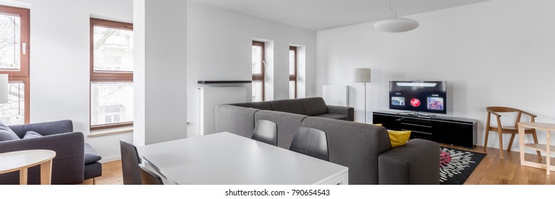 Modern home interior with white table and gray sofa, panorama
