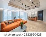 Modern Home Living Room. Luxurious Stylish Modern Apartment. Open Interior, Orange Color Sofa, Couch, Wardrobe, Furniture, Scandinavian Design. Flowers on the Table. Kitchen in Background. Wide Angle