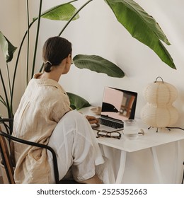 Modern Home Office Aesthetic with Woman, Laptop, and Large Indoor Plant - Powered by Shutterstock