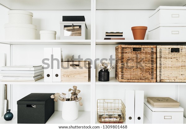 Modern home\
office cabinet interior design concept. White storage shelves rack\
with boxes, eucalyptus,\
decorations.
