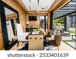 Modern home office with wooden walls, large mirror, and glass doors leading to an outdoor patio area.