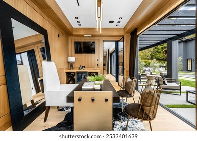 Modern home office with wooden walls, large mirror, and glass doors leading to an outdoor patio area.