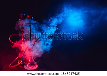 Modern hookah, shisha on a smoky black background with neon lighting and smoke. Place for your text