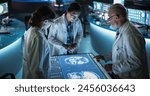 Modern Hospital Medical Research Center: Diverse Colleagues Gathered Around Interactive Touch Screen Table With MRI Scans Of Brain On Display. Three Doctors Discussing Innovative Brain Tumor Treatment