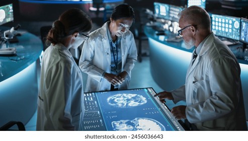 Modern Hospital Medical Research Center: Diverse Colleagues Gathered Around Interactive Touch Screen Table With MRI Scans Of Brain On Display. Three Doctors Discussing Innovative Brain Tumor Treatment - Powered by Shutterstock