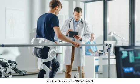 Modern Hospital Physical Therapy: Doctor Uses Tablet Computer, Helps Disabled Patient With Injury Walk On Treadmill Wearing Advanced Robotic Exoskeleton Legs. Physiotherapy Rehabilitation Technology