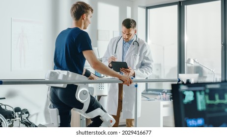 Modern Hospital Physical Therapy: Doctor Uses Tablet Computer, Helps Disabled Patient With Injury Walk On Treadmill Wearing Advanced Robotic Exoskeleton Legs. Physiotherapy Rehabilitation Technology