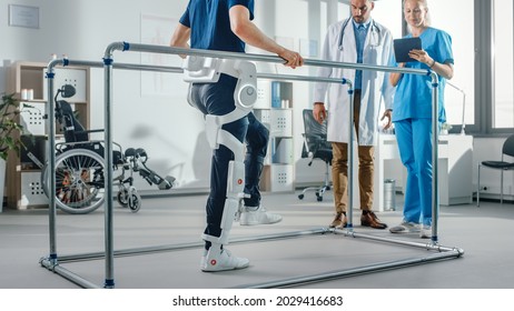 Modern Hospital Physical Therapy: Patient with Injury Walks Wearing Advanced Robotic Exoskeleton. Physiotherapy Rehabilitation Scientists, Engineers use Tablet Computer to Help Disabled Person - Shutterstock ID 2029416683