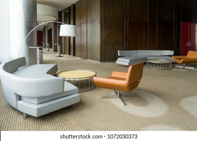 Modern Hotel Lobby With Hallway Or Office Lounge Room. Interior With Wood Paneling, Leather Sofa And Chairs, Round Metallic Tables And Floor Lamp. Downtown Workspace Design Concept