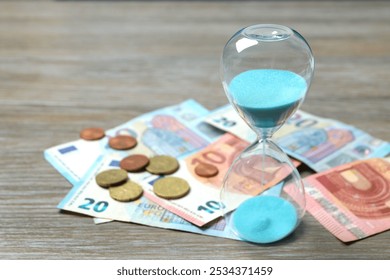 Modern hourglass and Euro banknotes and euro cents on wooden background. Hourglass time concept for business deadline, urgency and outcome of time - Powered by Shutterstock