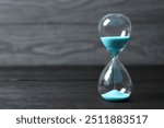 Modern hourglass on wooden background. Hourglass time concept for business deadline, urgency and outcome of time