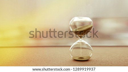Modern hourglass with sand color background, as time passing concept for business deadline, urgency and running out of time