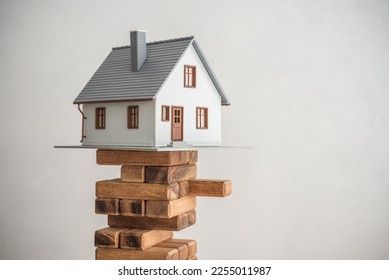 Modern house on wood tower block game white wall background copy space. Mortgage loan for buying home or real estate property, money risk management in financial, foreclosure and bankruptcy  concept.
