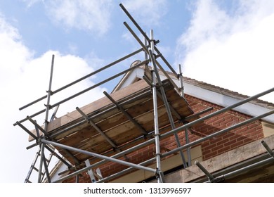 Modern House Roof Construction With Scaffold Pole Platform. New Build Domestic Building Against Blue Sky With Clouds