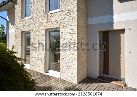 Modern house with stone cladding in summer sunshine with front door and windows, Austria, model house