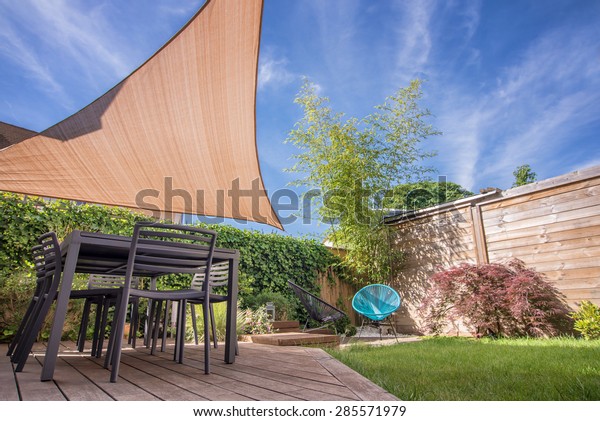 Modern\
house terrace in summer with table and shade sail\
