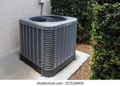 Modern HVAC Air Conditioner Unit On Concrete Slab Outside Of House. 